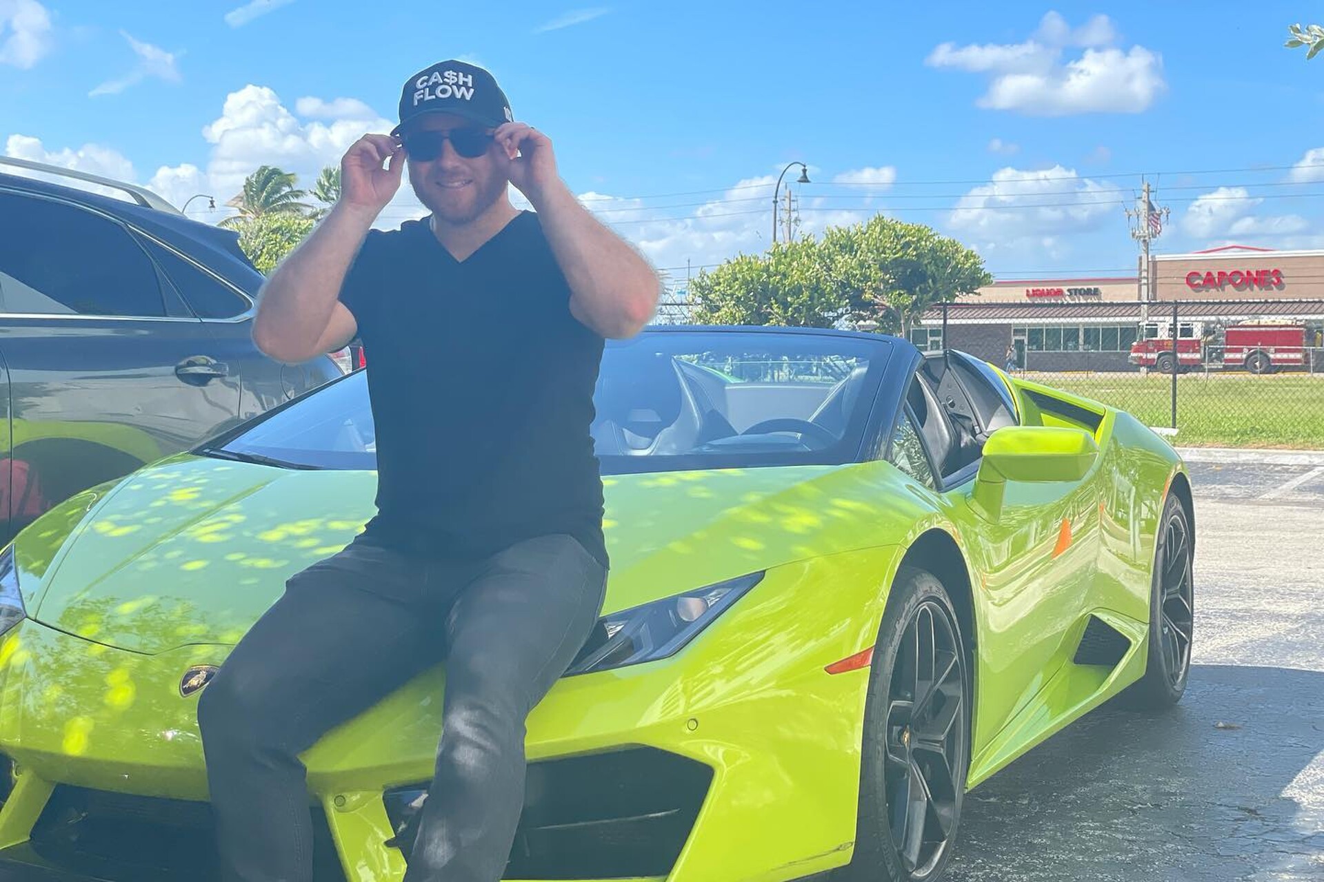 Nathan Danner wearing a Cash Flow hat sitting on a lime green Lamborghini 