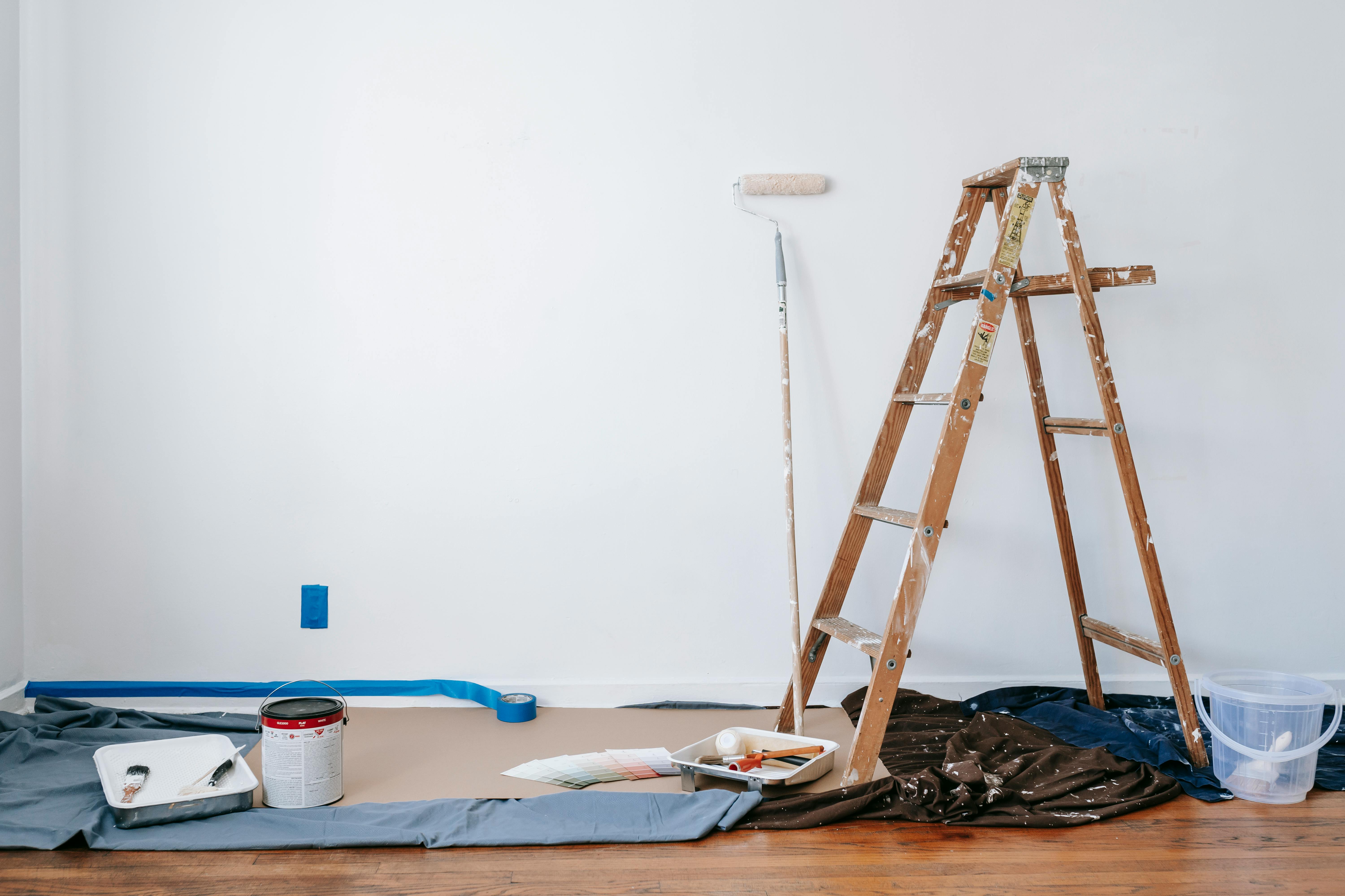 White wall with painting tools and ladder around