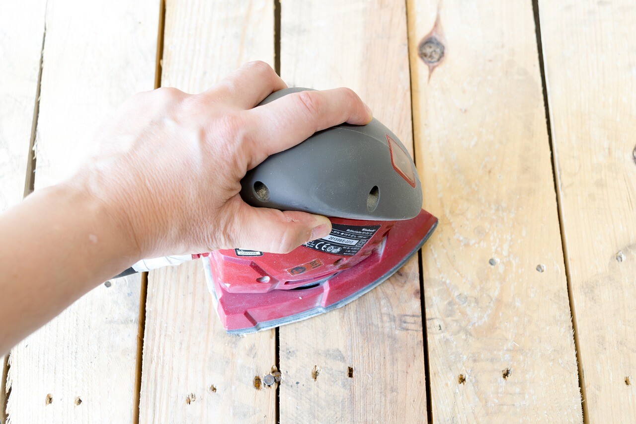 man holding sander on floorboards